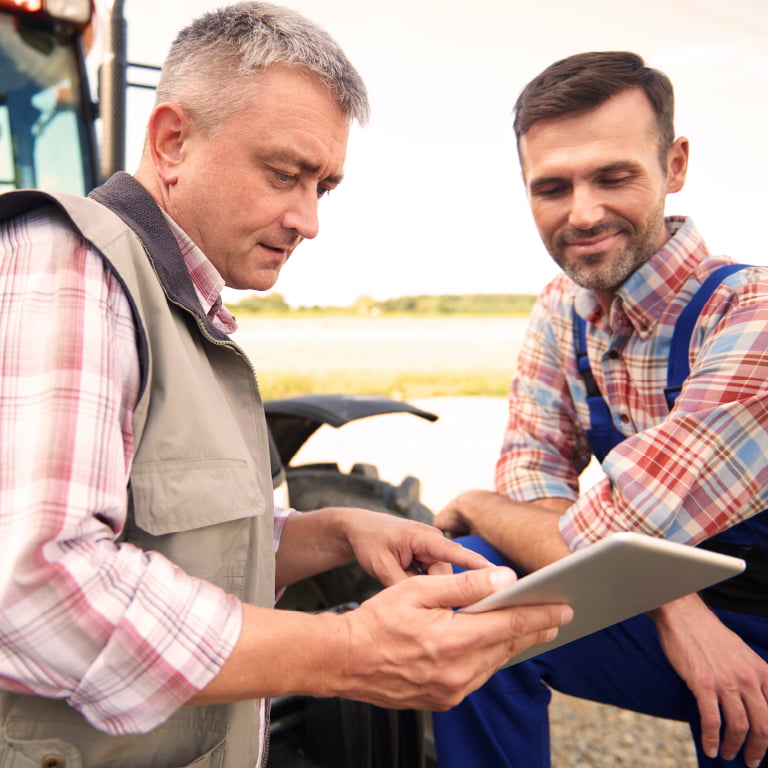 Un notaire explique quelque chose a un agriculteur a l'aide d'une tablette.